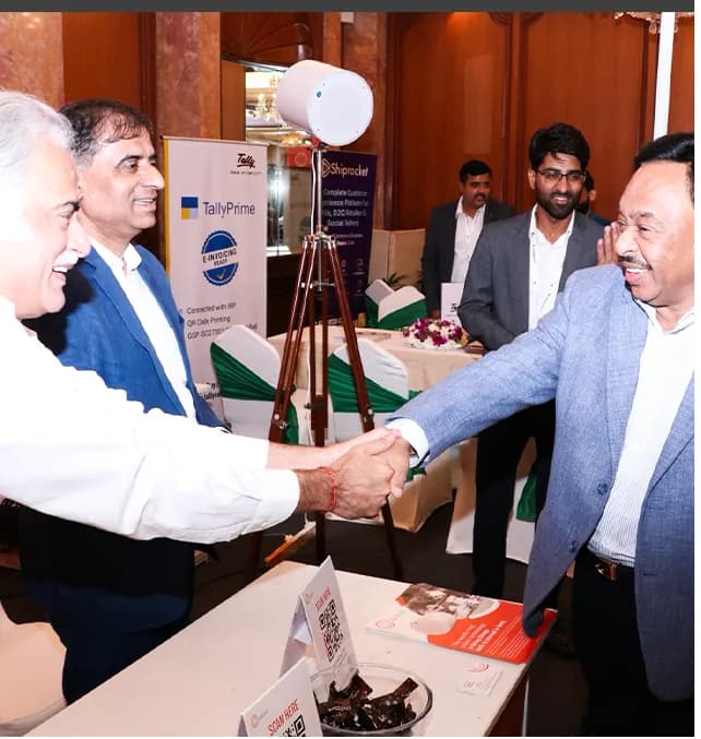 Two attendees shaking hands at an exhibitor's stall.